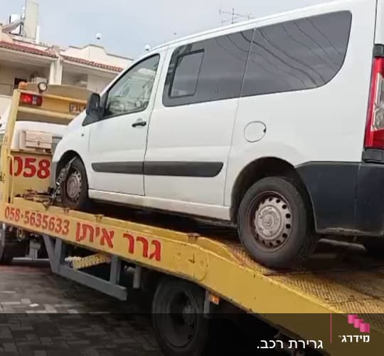 רכב לבן על גרר צהוב בשירותי דרך